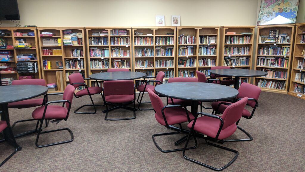 tables and chairs set up in a library with bookshelfs full of books in the background