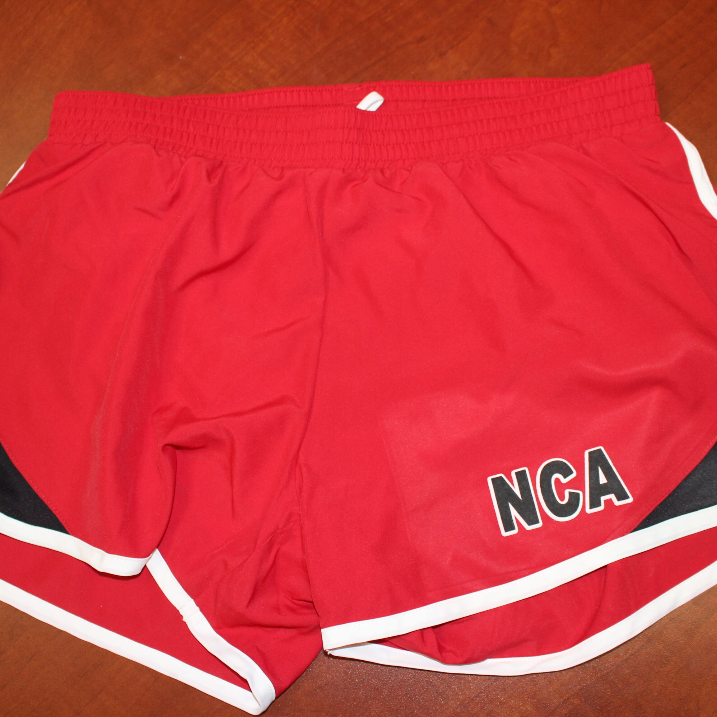 Red running shorts with the letters, "NCA" on them