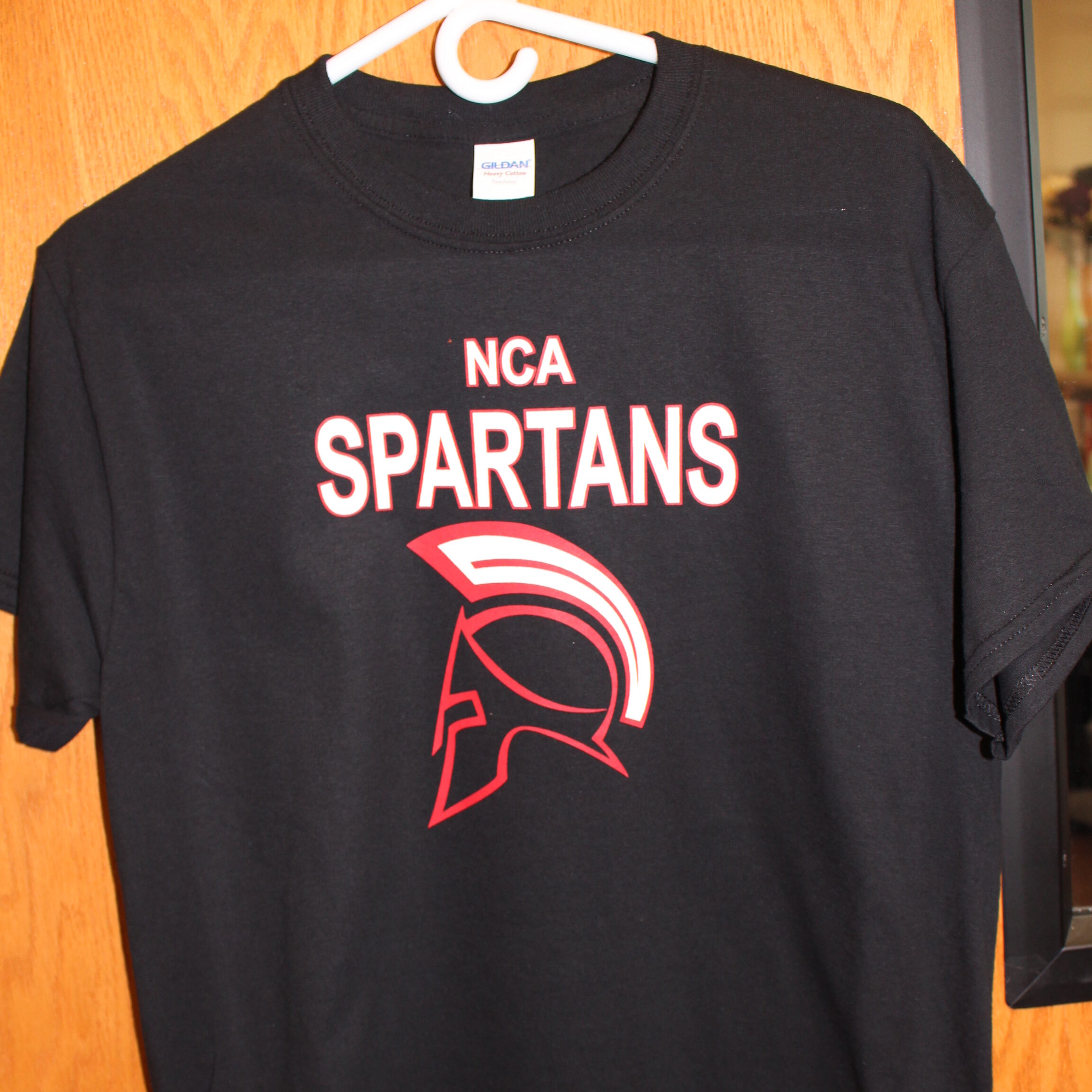 Black short sleeve t-shirt with the New Century Academy mascot on it